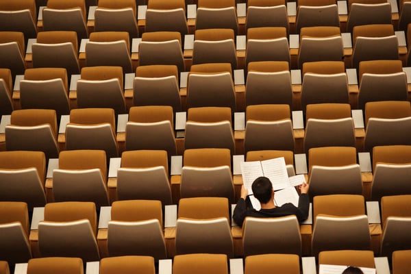 one student sitting among empty chairs